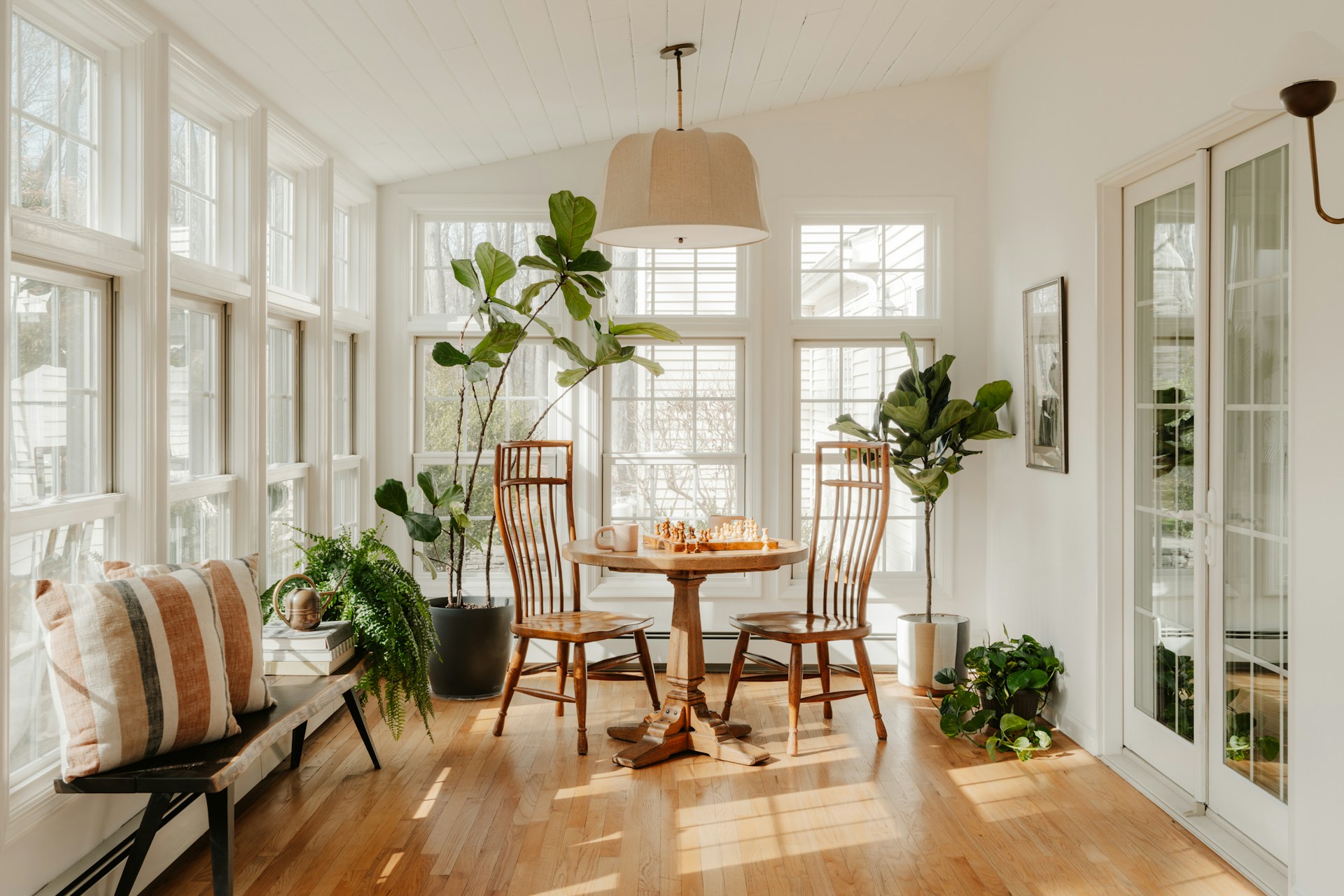 Bright sunroom with plants and dining table. Photo by Clay Banks.