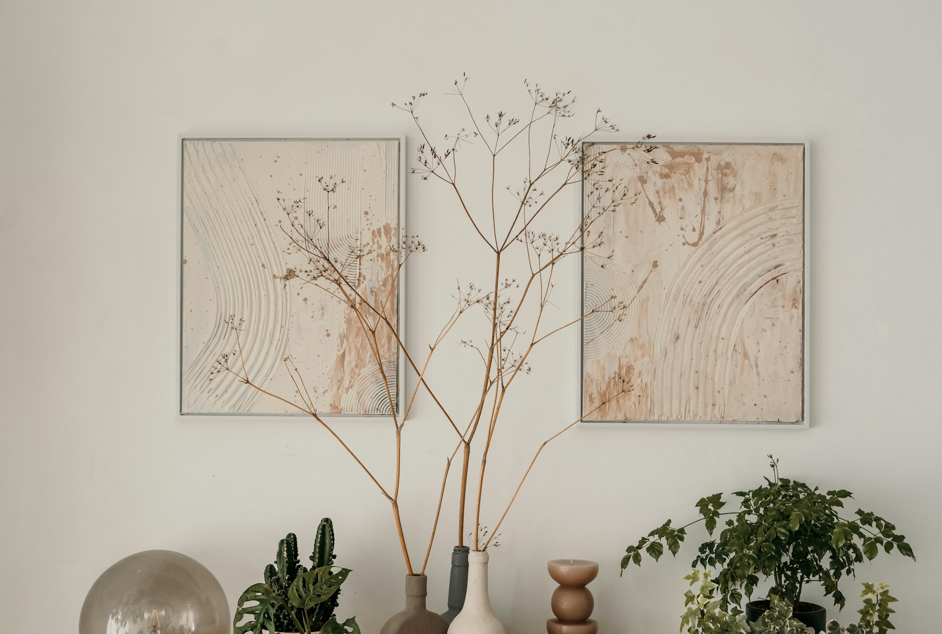 An earthy, minimalist display blending textured art with dried and fresh botanicals. Photo by Toa Heftiba.